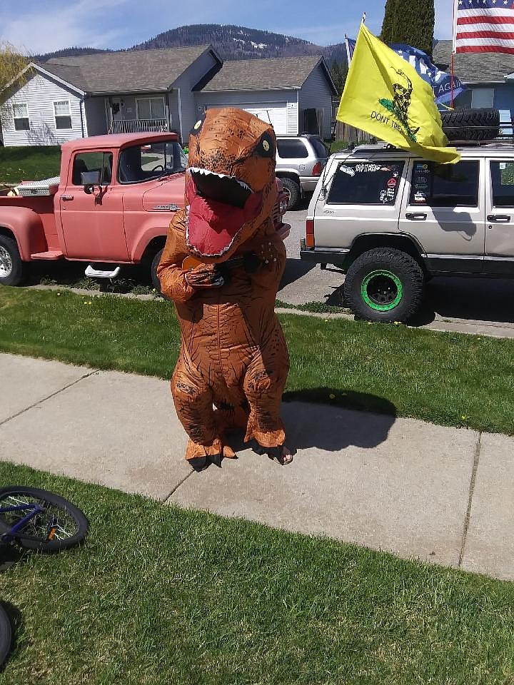 Rathdrum resident Barbara Adams on Sunday snapped this photo of a young man in a dinosaur costume playing a ukulele. The identity of the young man is unknown, but he brought a dino-sized serving of joy to community members and drivers. (Courtesy photo)