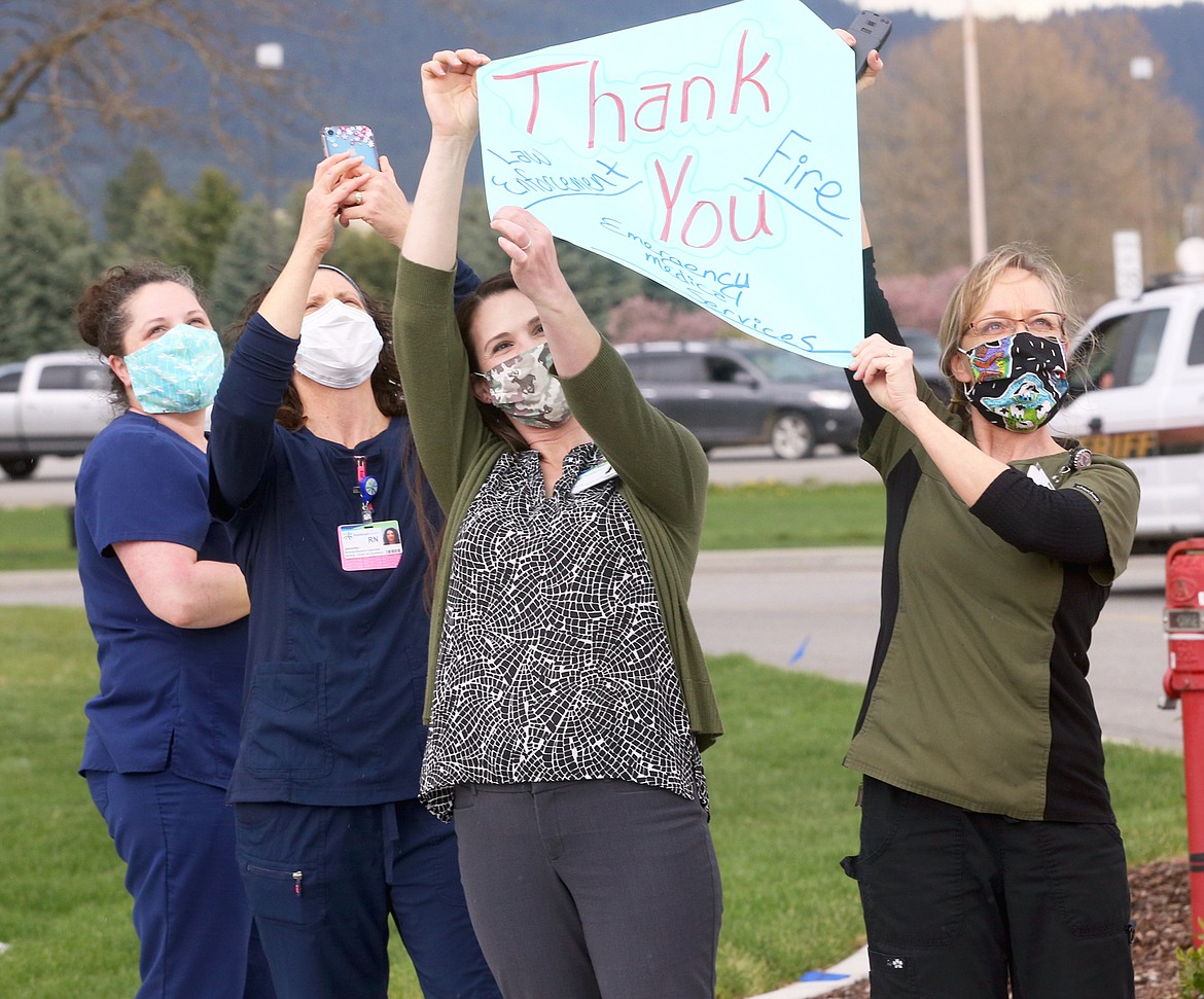 Kootenai Health’s Tammy Butler, right, and Jessica Hoover hold up a sign toward a helicopter that was part of the emergency services vehicle parade on Wednesday.