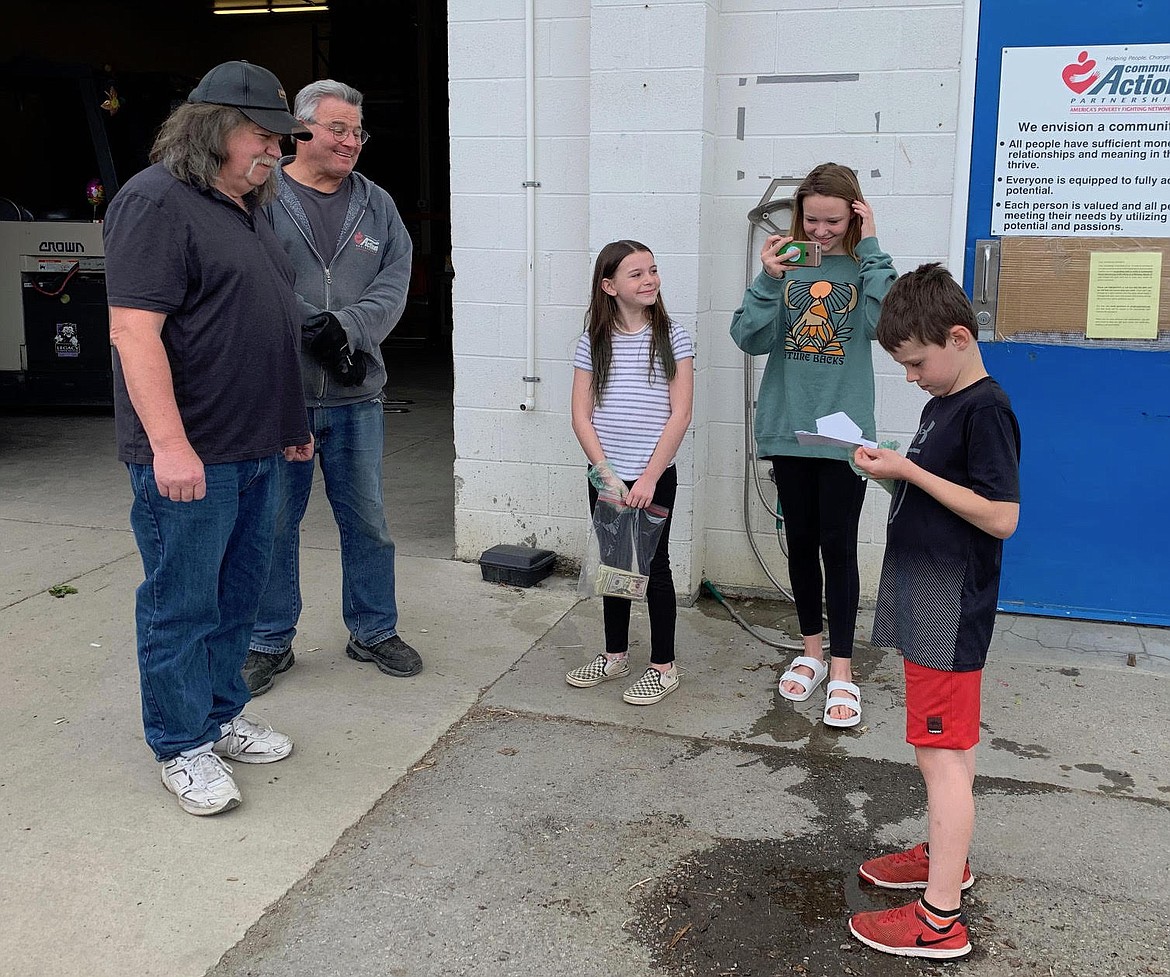 Community Action Partnership Coeur d'Alene Food Bank manager Darrell Rickard, left, and warehouse worker Howard Richter accept a donation of $1,110 raised by a group of local youths who sold ice cream to support their community. Also pictured: siblings Scarlett, center, Sophia and Sam Green. (Courtesy photo)