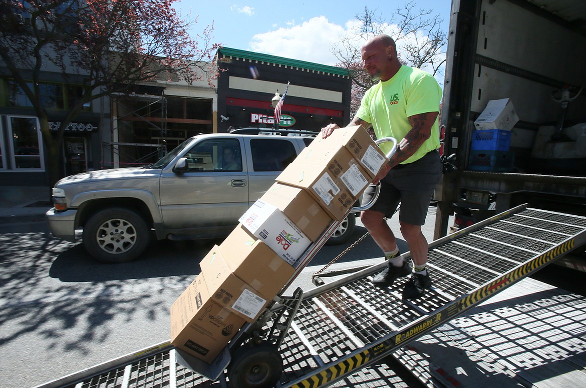 U.S. Foods driver and supervisor Lane Bos rolls boxes of food down a ramp to deliver to Pita Pit on Friday, the first day downtown Coeur d'Alene shops could reopen following Gov. Brad Little's stay-home order. Dining rooms are still closed until stage 2 in mid-May, but many restaurants are offering delivery, carry out and curbside orders. (DEVIN WEEKS/Press)