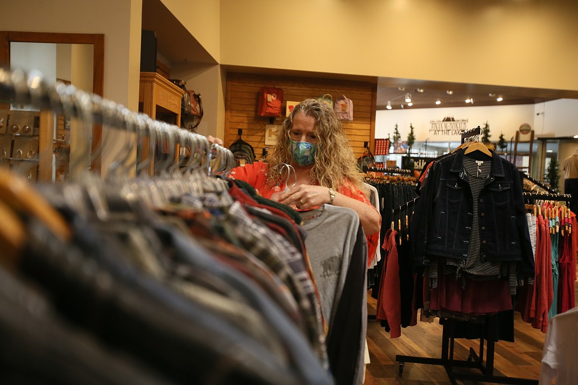 Finan McDonald at the Lake co-owner Twilla Ford hangs men's clothing on a rack Friday as stores throughout downtown welcome their first guests since pandemic closures. Finan McDonald has a variety of items on clearance right now, as well as new products to offer customers. (DEVIN WEEKS/Press)