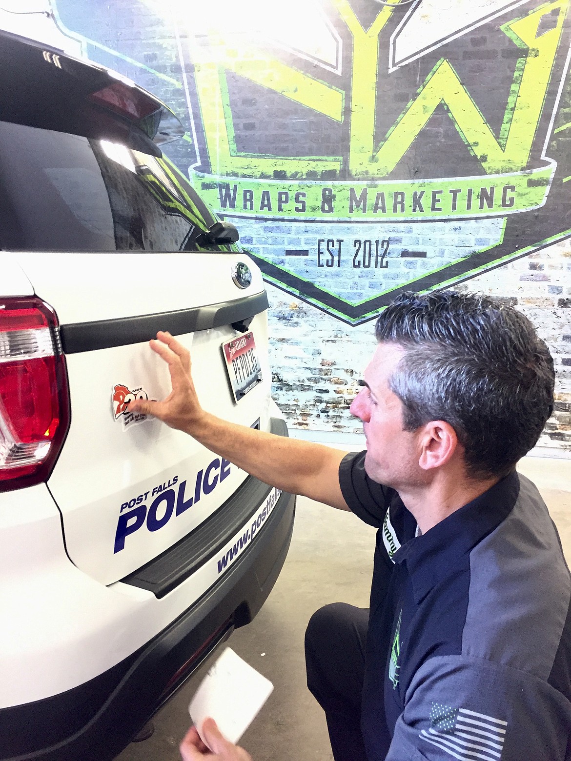 Sam Carlino, owner of CW Wraps, affixes a sticker to a Post Falls Police car, honoring the Post Falls High School class of 2020. Carlino’s team designed, printed, and donated 100 stickers for the city to use on its vehicles.