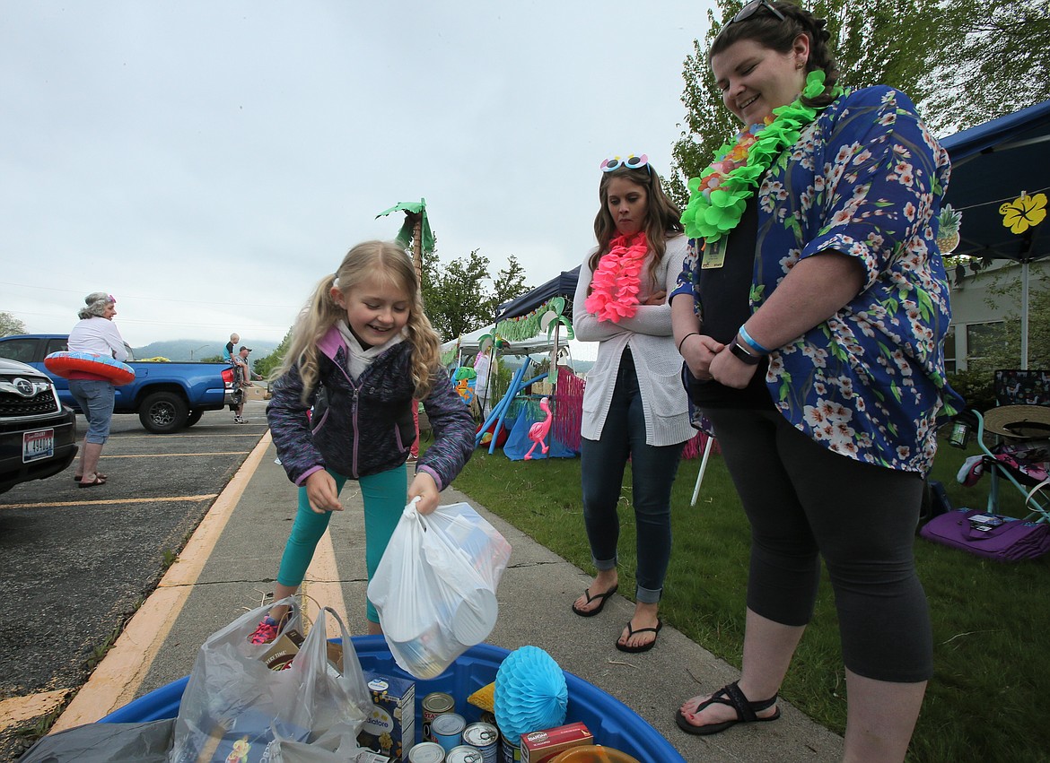 Fourth-grader Skylar Lenz happily drops a bag of food donations into a collection pool during a food drive at Mullan Trail Elementary on Friday. Also pictured: Fourth-grade teachers Heather Corey, right, and Sarah Geibel.