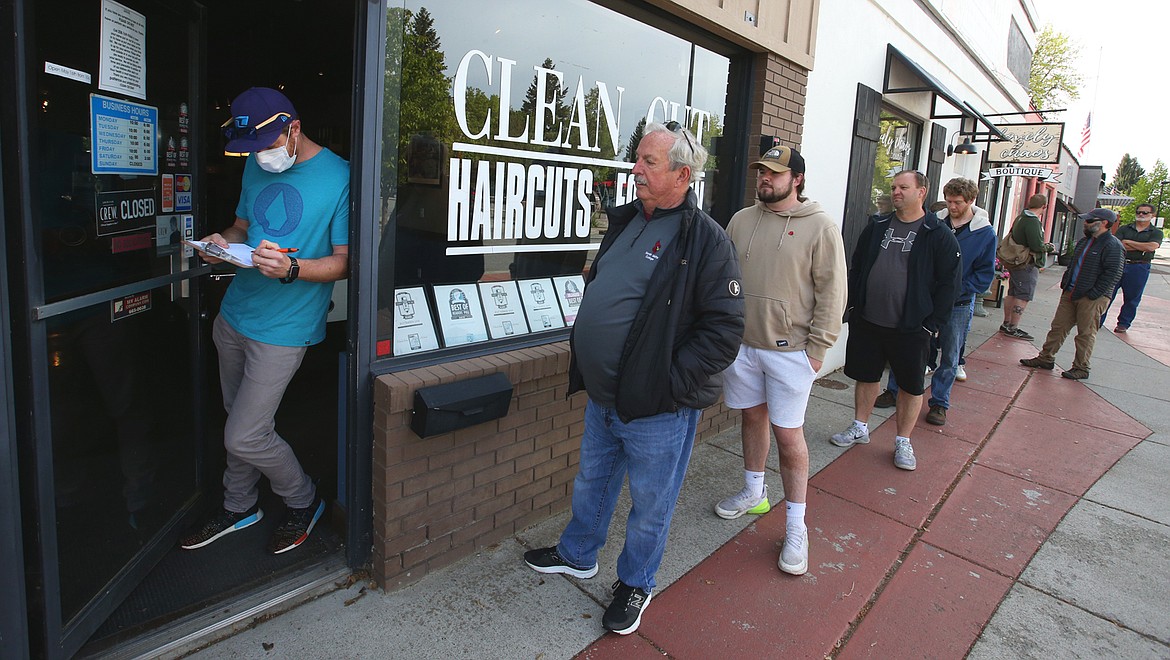 Eric Carpenter, owner of Clean Cuts Haircuts for Men, prepares to let customers come in and takes names for appointments Saturday.