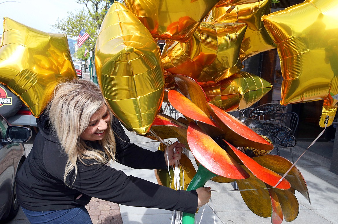 BILL BULEY/Press 
 Emily Boyd of the Coeur d’Alene Downtown Association places gold star ballons along Sherman Avenue Saturday morning.