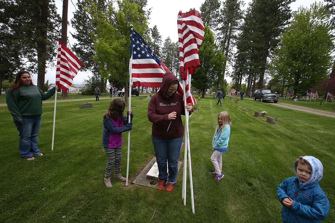 Becky Fisher, children Hannah, Isabella and Sage., and friend Beth Hall, left, plant flags at the gravesites of veterans at Evergreen Cemetery Friday.