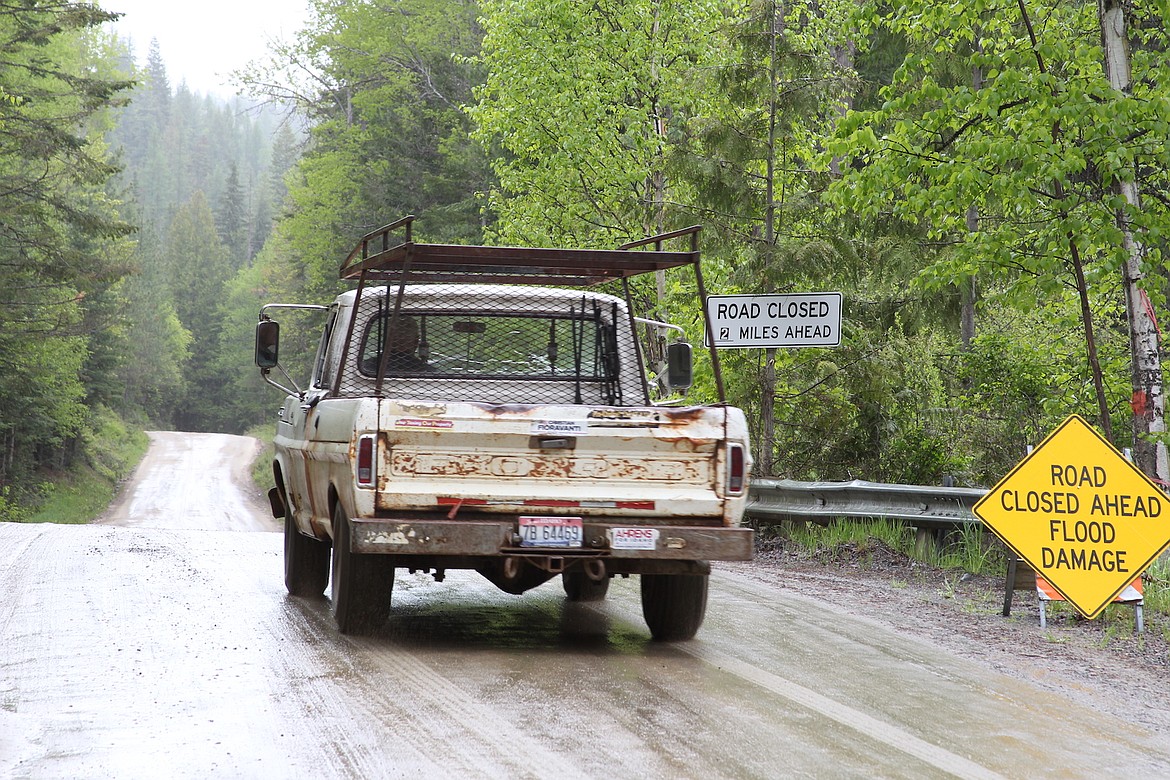 (Photo by KEITH KINNAIRD) 
 A motorist passes by signs warning of the washout on Grouse Creek Road.