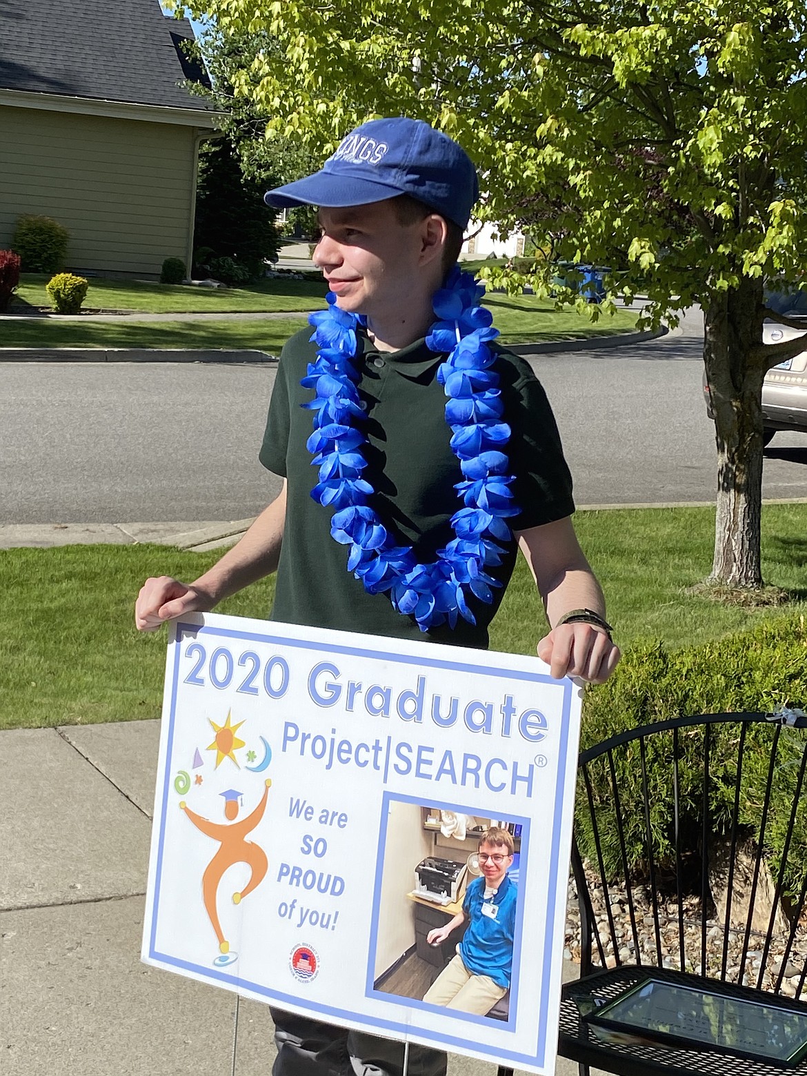 In a celebration lei, Project SEARCH graduate James Sane holds a sign sharing his accomplishments after completing the program during a surprise drive-by graduation celebration Wednesday evening.