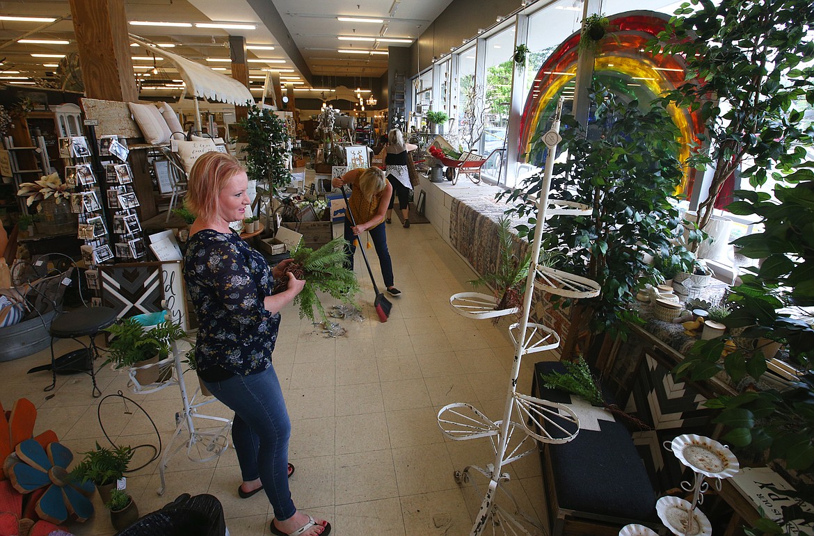 BILL BULEY/Press 
 Megan Eatock, owner, helps clean up after a car crashed into the front window of Midtown Home and Vintage Market on Monday.