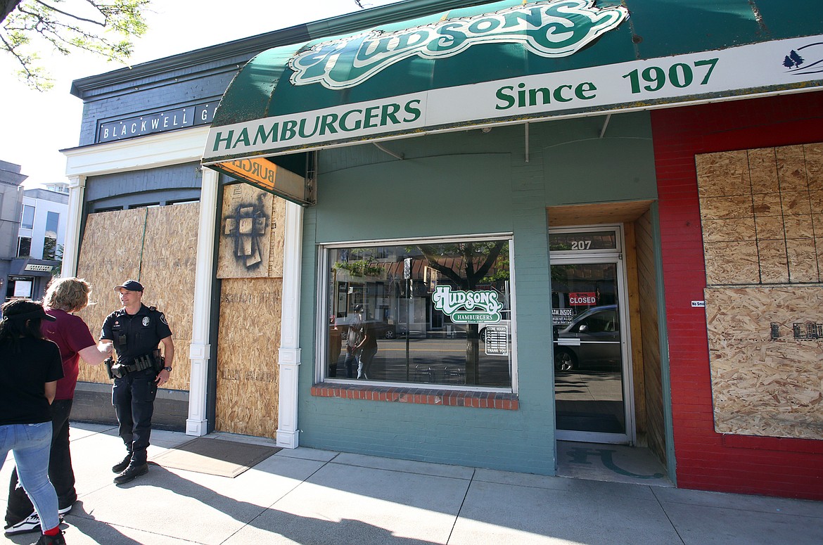 BILL BULEY/Press 
 A Coeur d'Alene police officer talks to passersby as he patrols on Sherman Avenue on Monday evening. Some stores boarded windows due to reports of rioters coming to Coeur d'Alene.