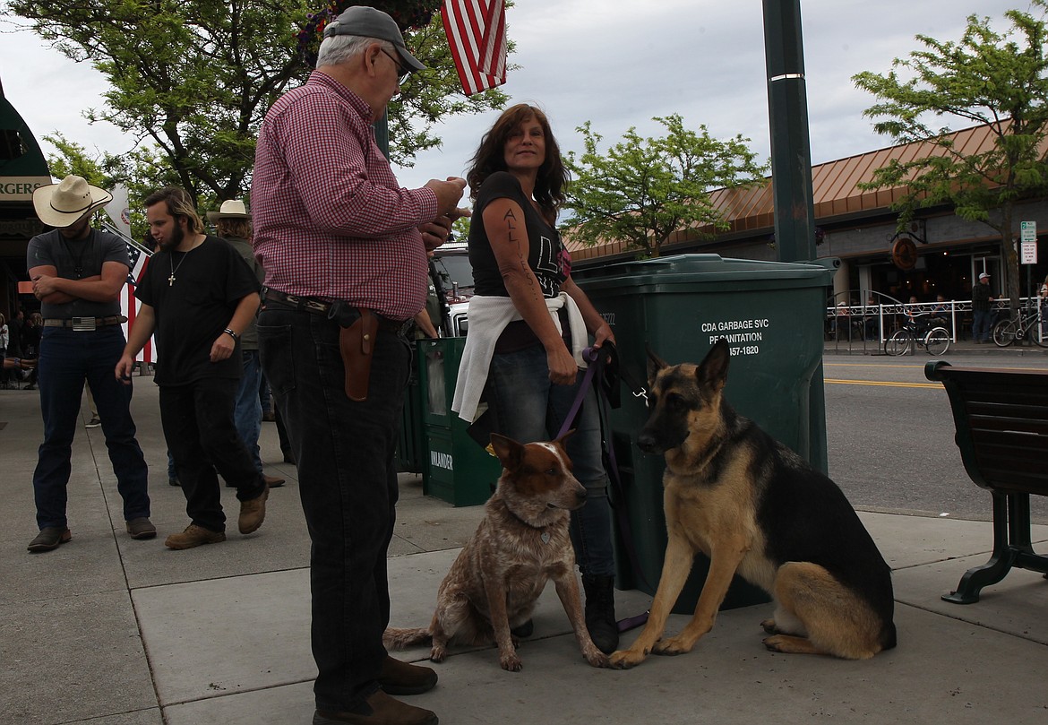 Coeur d’Alene dog trainer Taresa Balanesi, with her dogs Klaus and Jacques, discuss Tuesday’s protests with  Mike Glass of Hayden, near the corner of Sherman Avenue and Second Street.
RALPH BARTHOLDT/Press