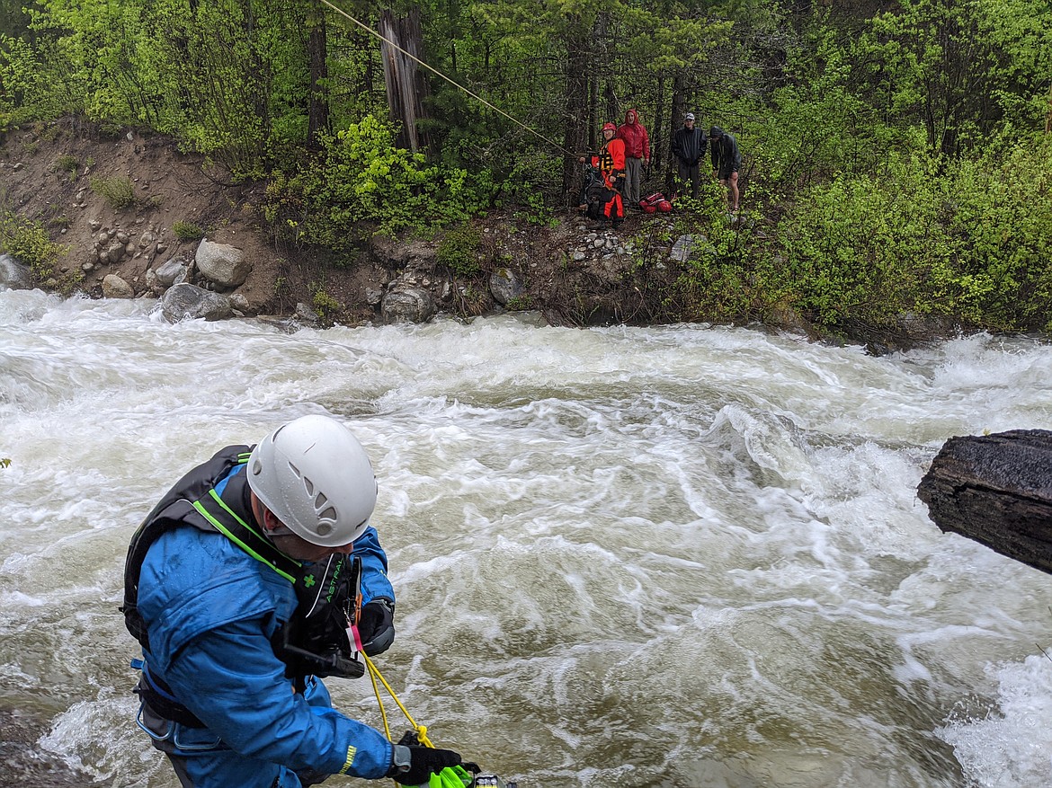 Bennett works with rescuer Adam Reeves across the stream, standing next to the three stranded hikers.