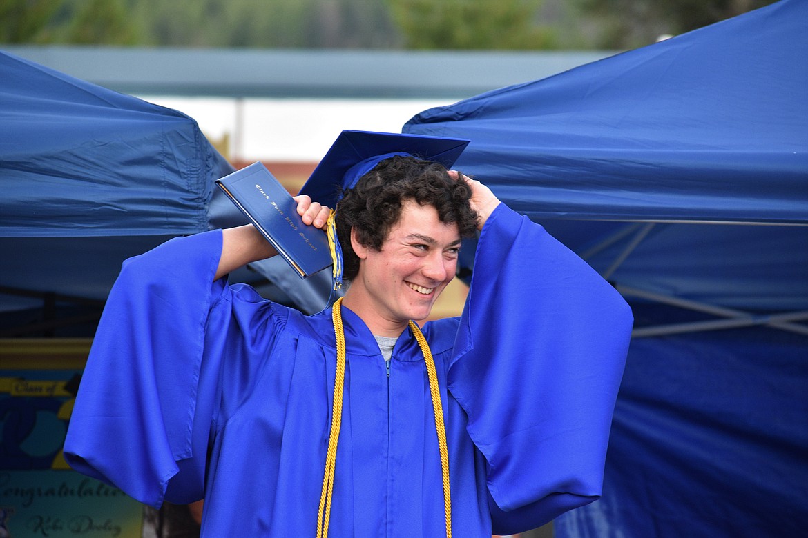(Photo by DYLAN GREENE) 
 Chuck Henderson smiles as he puts his cap back on after throwing it in the area to celebrate graduating.