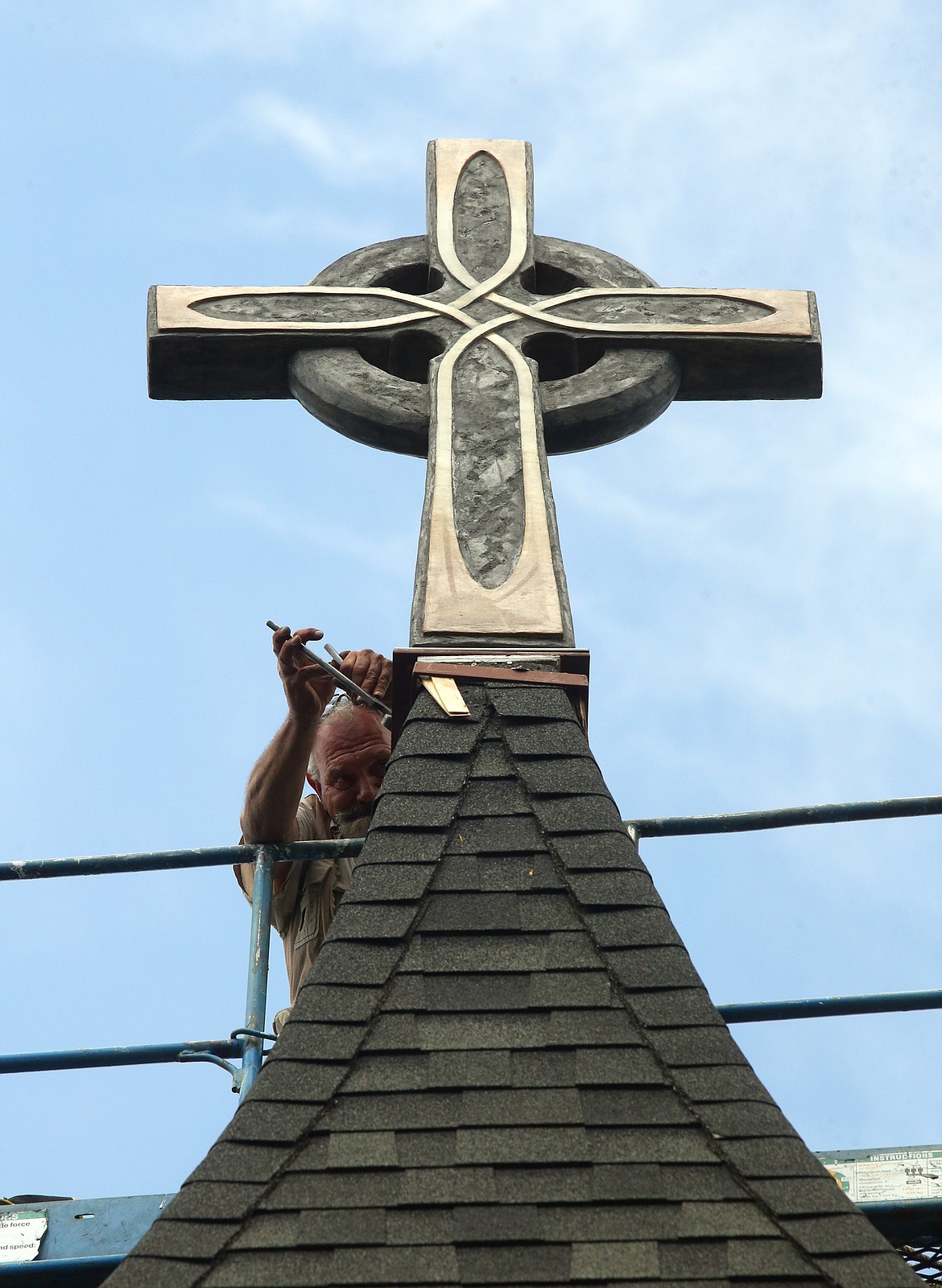 BILL BULEY/Press 
 David Brooks secures the new cross on the steeple at St. Luke’s Episcopal Church on Thursday.