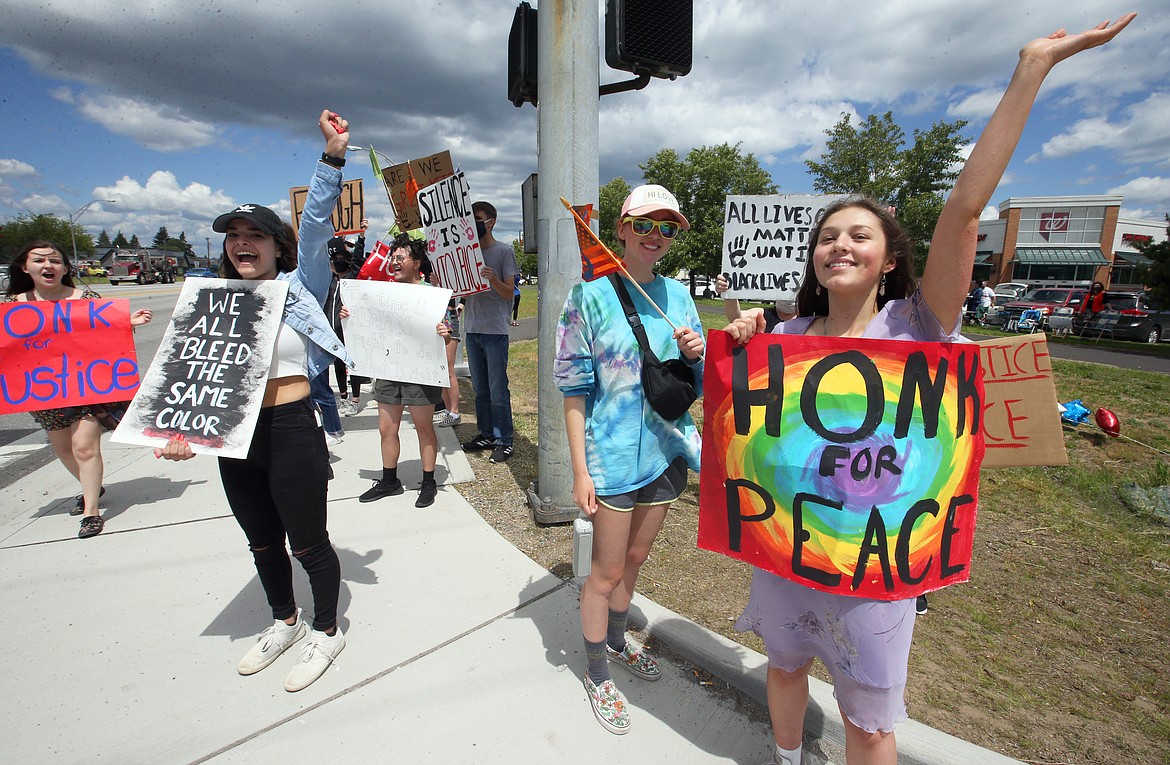 Laurali Strong, right, is joined by Elizabeth Cook, left, and Vanessa Dimberg at a rally for peace at U.S. 95 and Appleway Avenue on Thursday.