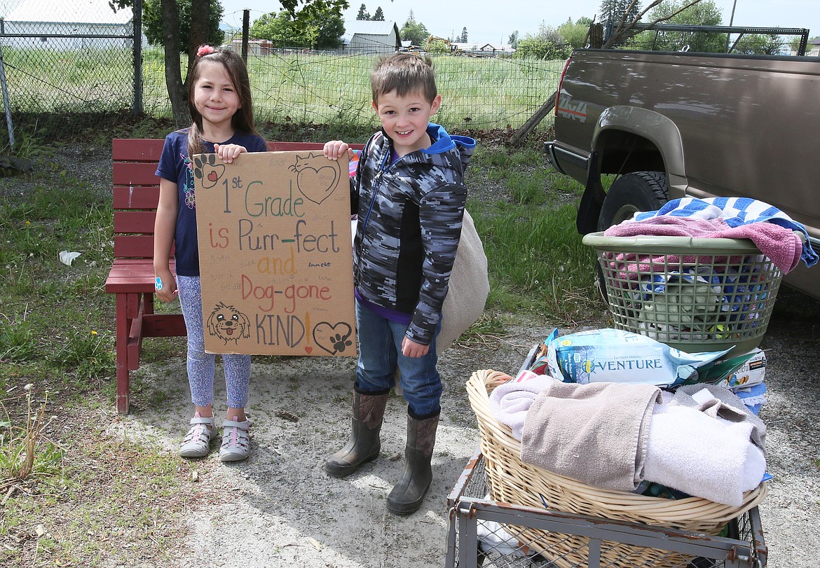Genesis Preparatory Academy first-graders and best buddies Violet Thomason and Miles Arrotta hold up a sign that reads “1st grade is purr-fect and dog-gone kind” on Friday during a trip to deliver donations of food and supplies to Kootenai Humane Society. (DEVIN WEEKS/Press)