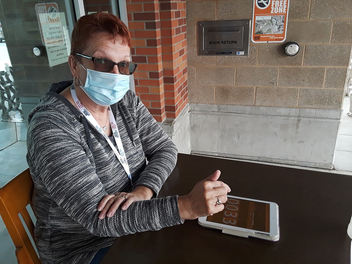 Cheryl Christiansen of the Coeur d’Alene Library takes a turn as a greeter outside its Front Street doors. Greeters will offer guests hand sanitizer and masks — both optional — while she maintain a count of less than 50 visitors at one time.