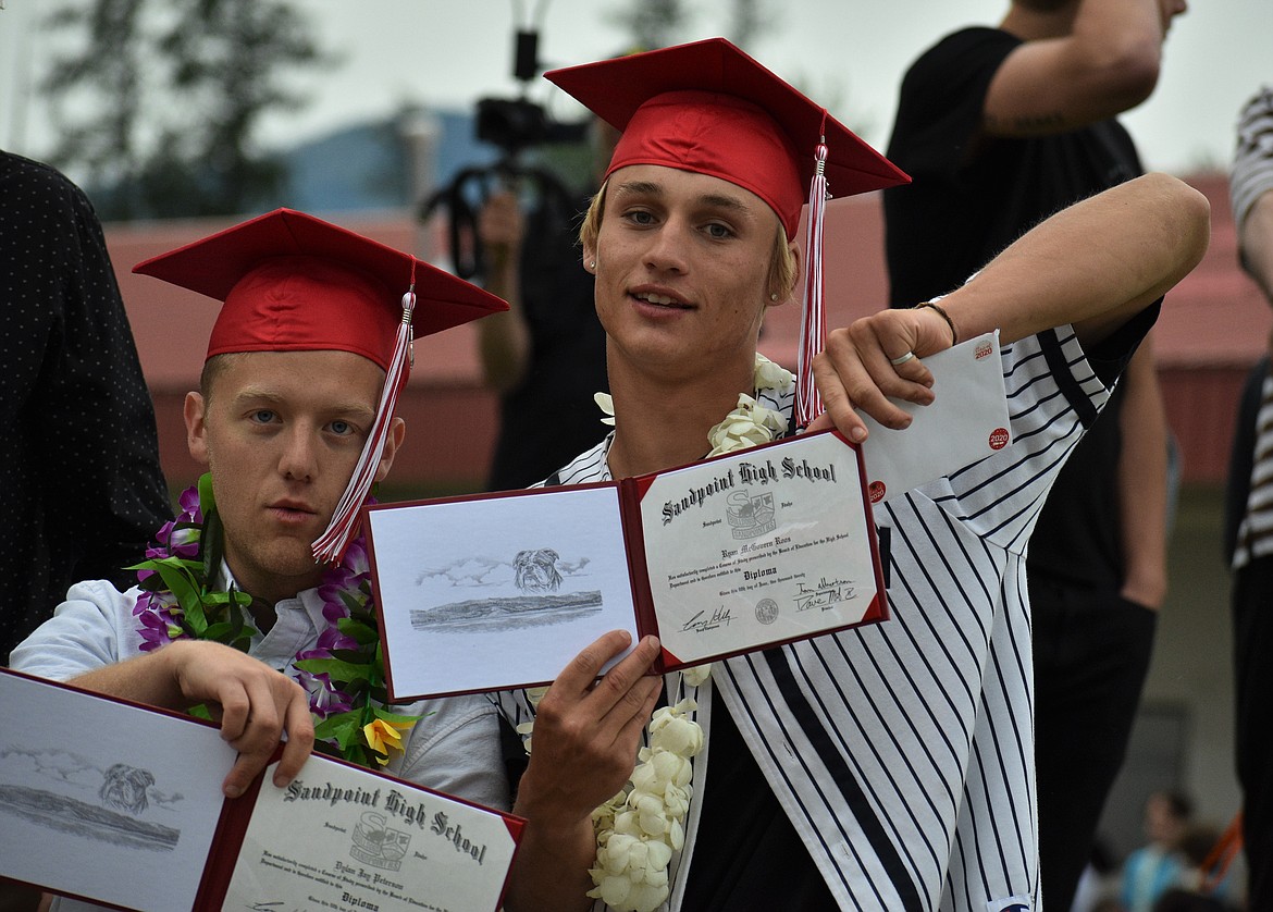Dylan Peterson (left) and Ryan Roos hold up their diplomas after turning in their gowns during SHS graduation on Friday night.