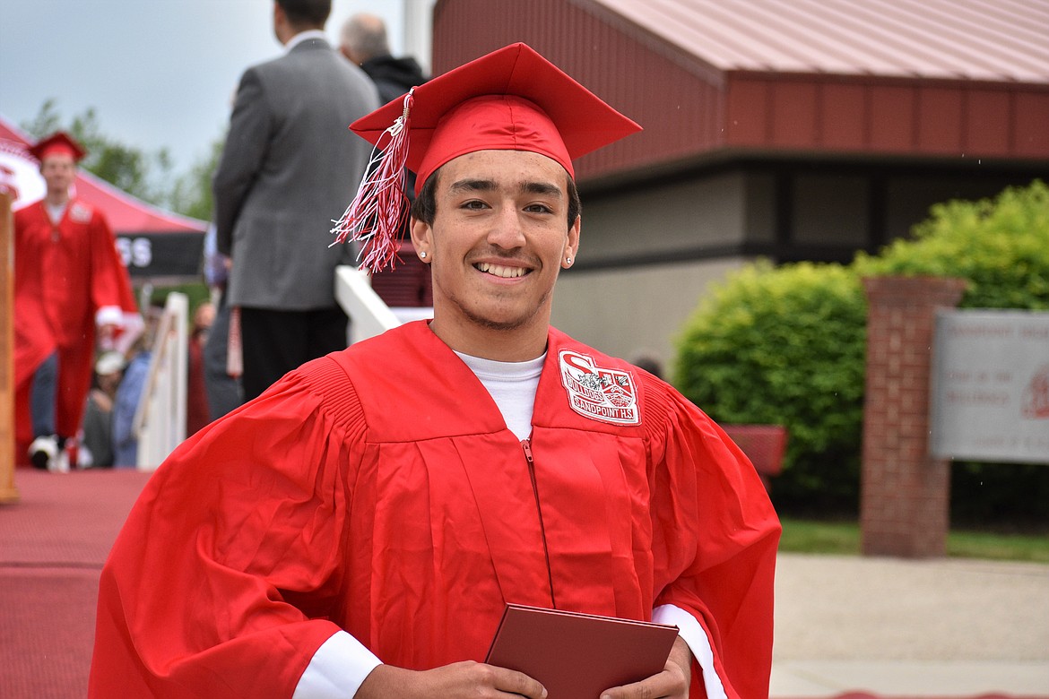 (Photo by DYLAN GREENE) 
 Isaiah Caralis smiles after receiving his diploma.