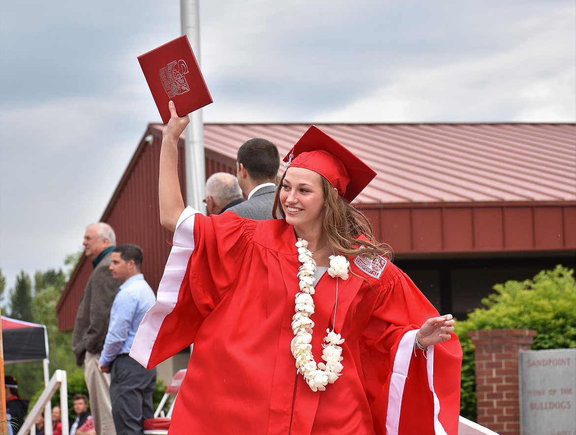 (Photo by DYLAN GREENE) 
 Samantha Ferguson holds up her diploma and looks toward her family in the crowd.