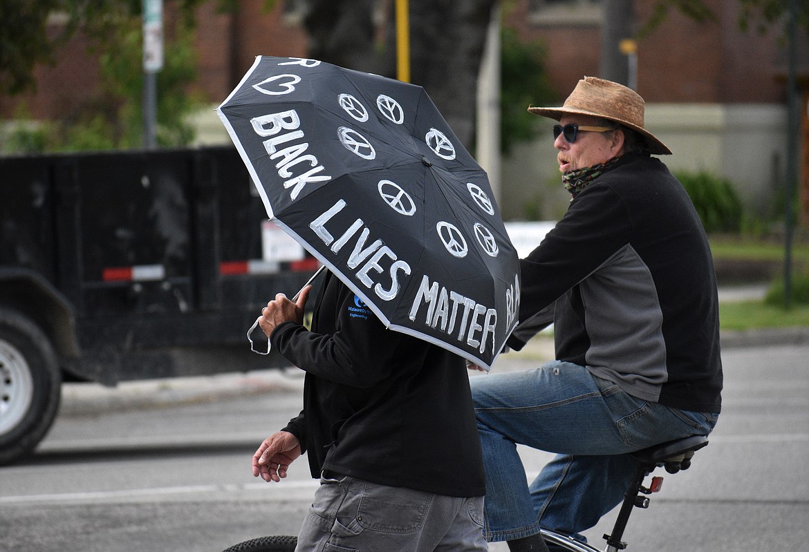 (Photo by DYLAN GREENE) 
 A protester carries an umbrella with hearts, peace signs and the words Black Lives Matter on it.