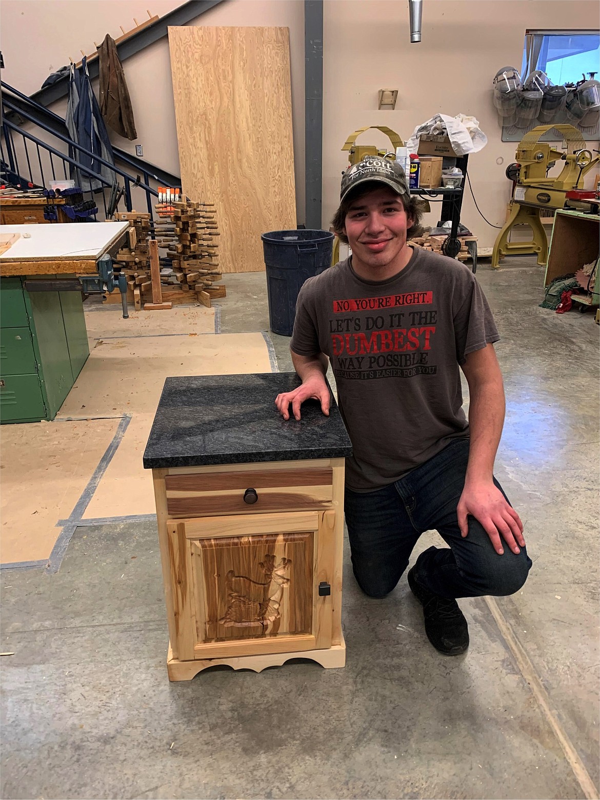 Austen Jones (senior) and his first semester cabinet. As part of the CMM2 class he was able to learn raised panel carving with CNC and carved the jumping deer in to the front of his cabinet. He was given a piece of granite to use as the top, setting his project apart, and giving it a special look.