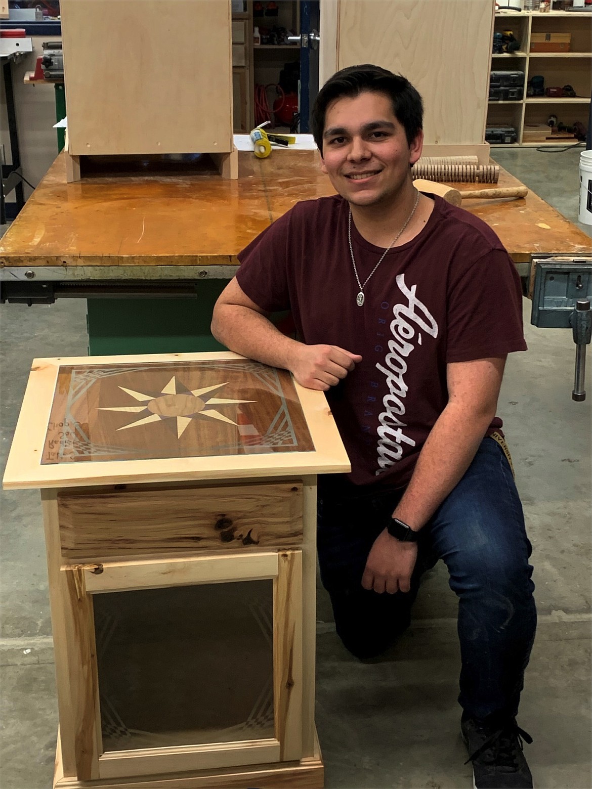 Michael Youngwirth and his first semester cabinet project. As a CMM3 student he applied the advanced veneering and glass etching skills to the project. His top panel is veneered with a variety of woods using the Parquetry method (geometric pattern inlays). He hand drew and etched the top and door glass. Adding class to his cabinet top set his project apart.