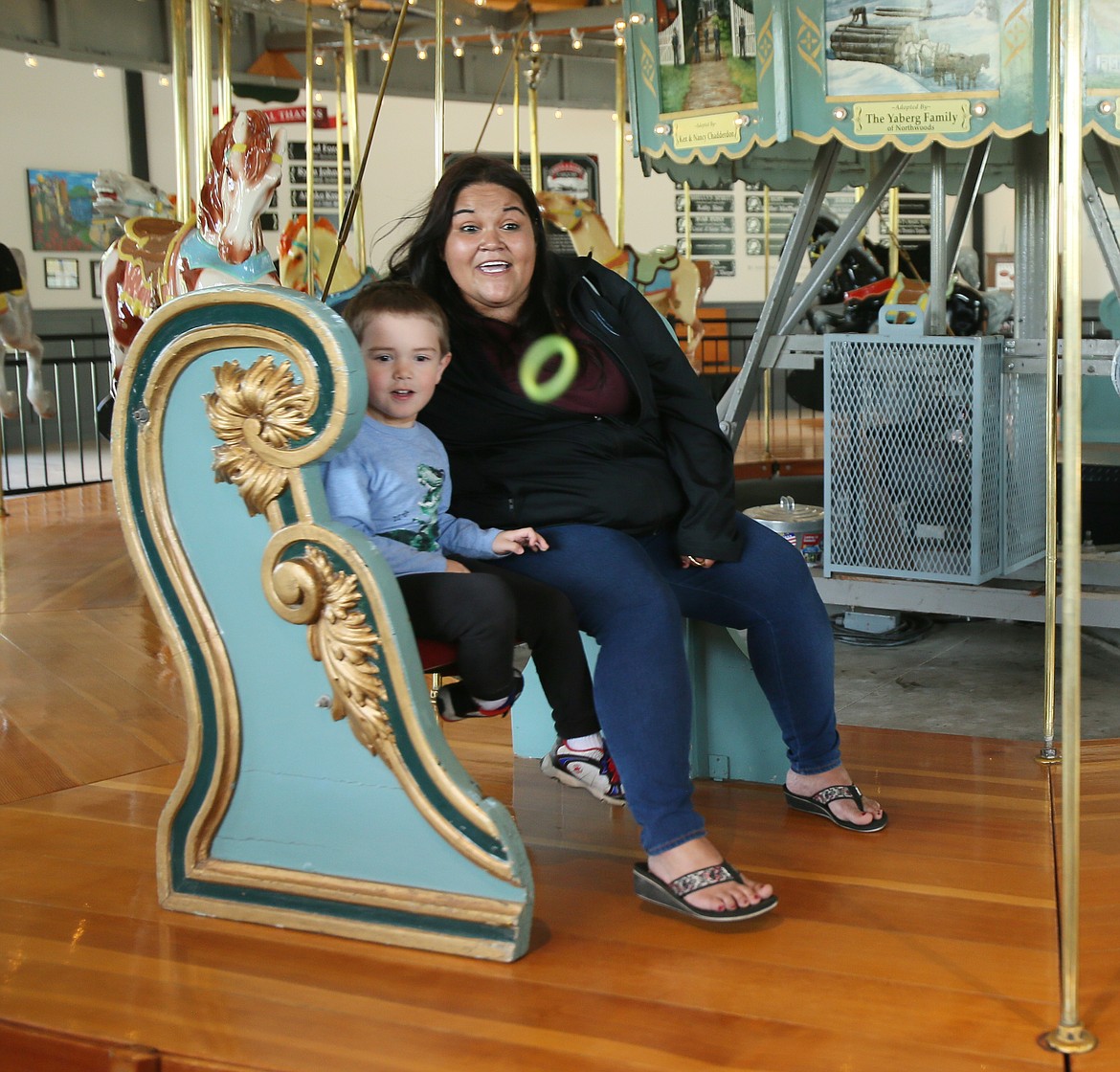 Mom Amy Murillo and son Gavin Martin, 4, watch in excitement as a green ring Gavin tossed makes its way toward the target on Monday at the Coeur d'Alene Carousel. The carousel is now open seven days a week and available as a venue for birthday parties and other events. (DEVIN WEEKS/Press)