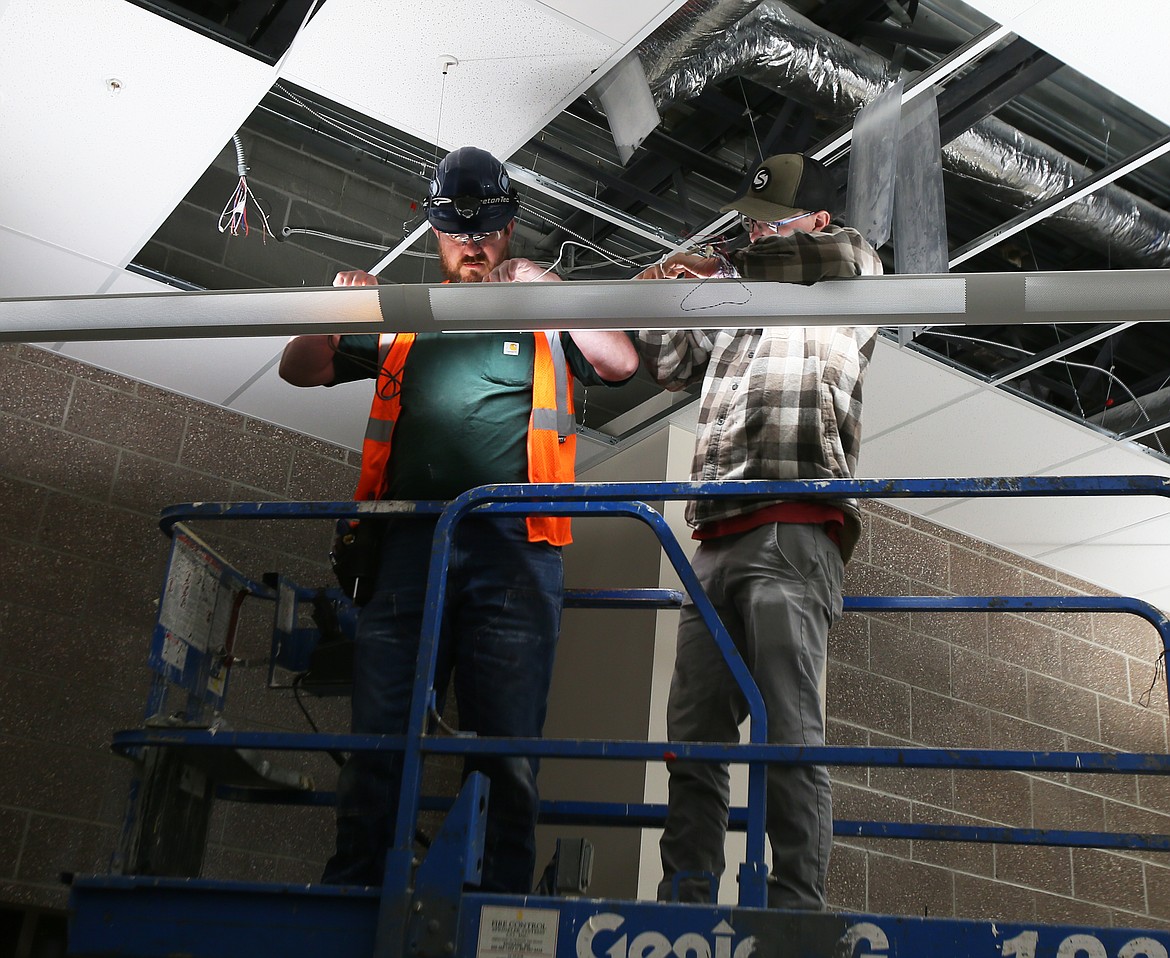 Salmon Electric workers Mike McLaughlin, left, and John Fortuny on Wednesday morning tackle a lighting project in the library of the new Treaty Rock Elementary School being built in Post Falls. (DEVIN WEEKS/Press)