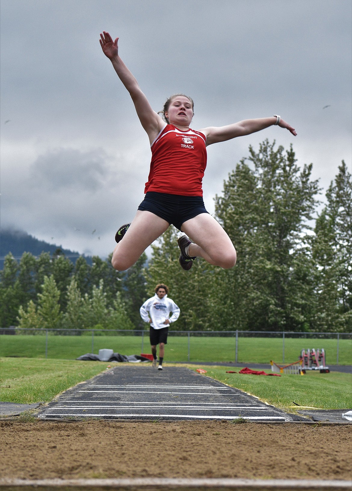 (Photo by DYLAN GREENE) 
 Senior Maddie Morgan leaps into the pit during the long jump.