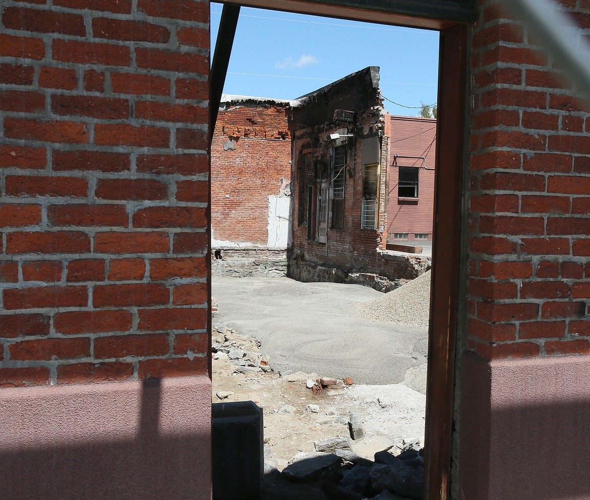 Peeking through a chain link fence from the south, passersby can see a burned wall that used to be the back of Schmidty's Burgers before the old brick building at the 200 block of North Fourth Street was destroyed in a fire. Plans are in motion to rebuild on the site and add a second floor. (DEVIN WEEKS/Press)