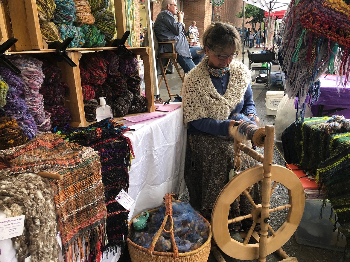 Holcomb demonstrates spinning on a wheel at her stand during the Wednesday Kootenai County Farmers’ Market last week. She’s been selling her yarn and other creations there since 2005.
[Photo by Elena Johnson]