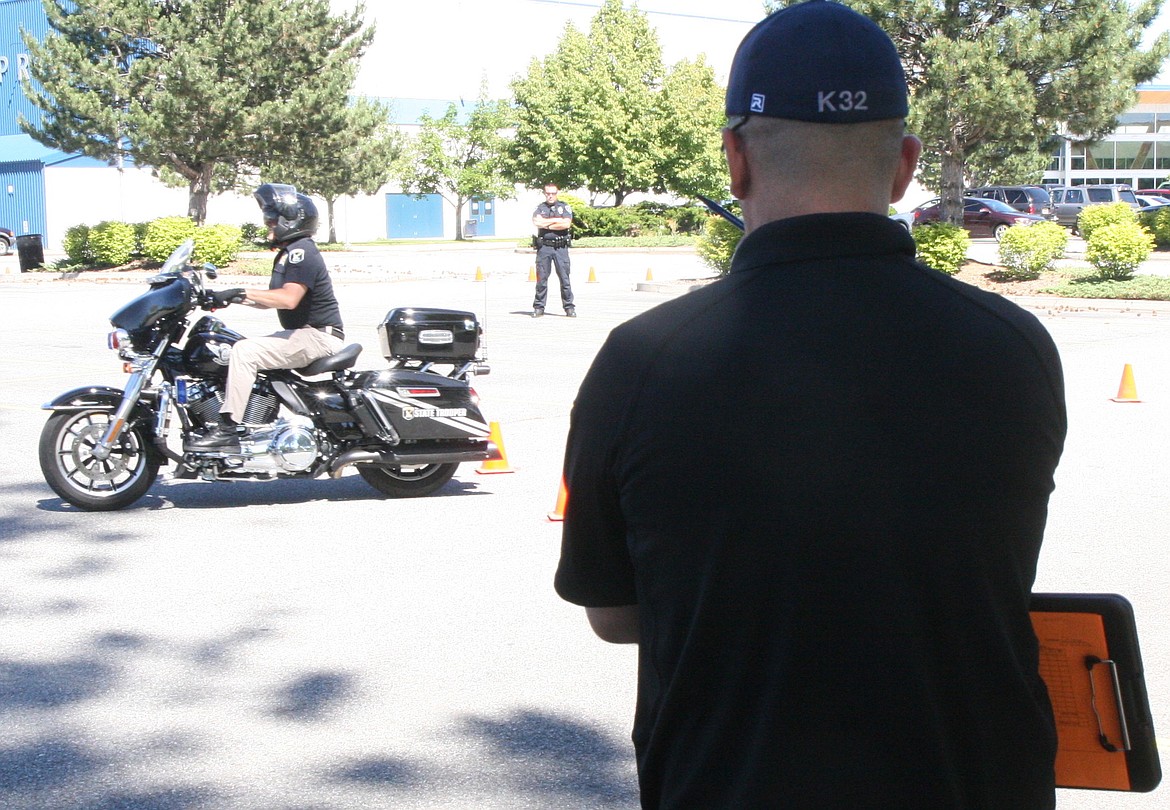 Trainer Shane Avriett looks on Tuesday as Todd McDevitt trundles through an obstacle course in the CHS parking lot as part of the certification process to earn his motorcycle wings.