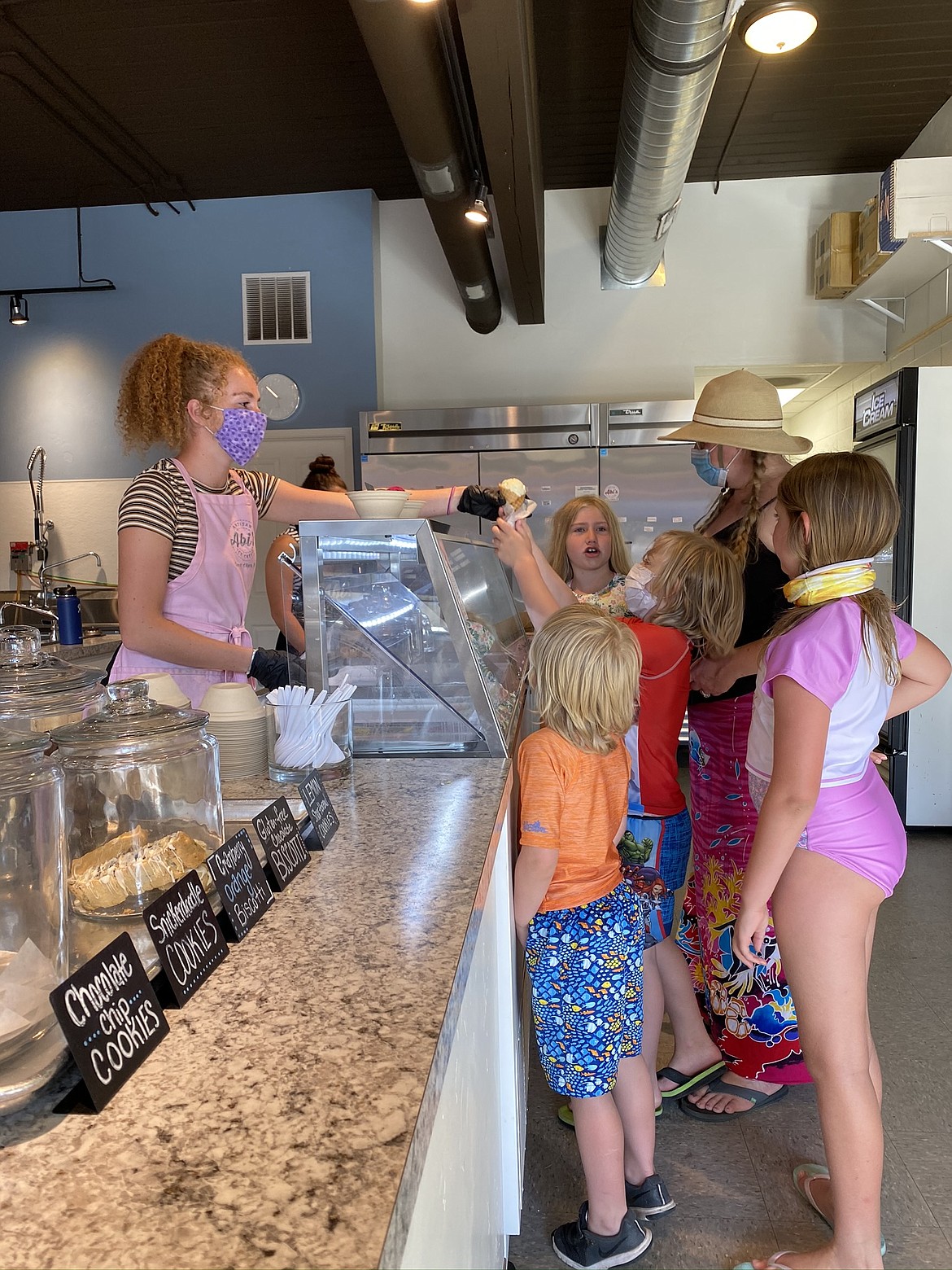 Savannah Butler, left, of Abi’s Ice Cream serves a family delicious relief on a hot Friday afternoon.
Abi’s owner Maren Scoggins said steering customers toward other local businesses was critical this summer, as the cancellations of big community draws like Car d’Lane and the Fourth of July parade are pulling reliable foot traffic off the books.