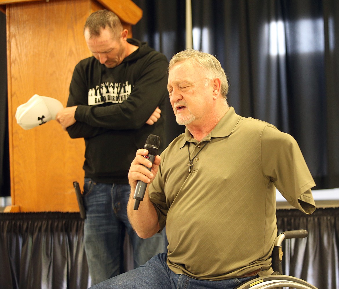 Pastor Tim Scott gives the opening prayer while Brent Surplus bows his head during Sunday’s dinner at the Kootenai County Fairgrounds.