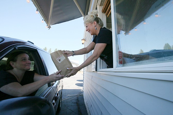 Friendly Midtown Drive Up Deli employee Lori Nirk hands loyal customer Melisa Coontz a bag of delicious food.