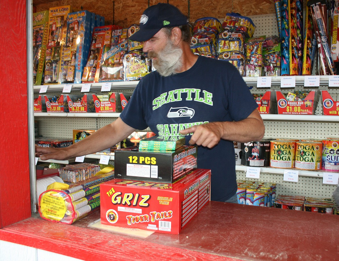 Steve Holmes rings up a customer’s order just after the fireworks stand operated by the Sand Scorpions off-road vehicle club opened Sunday.