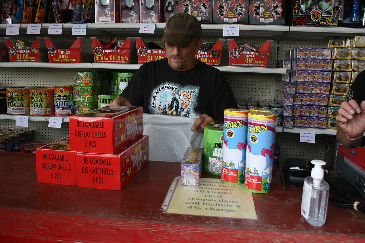 Fireworks stand manager Duane Strong bags  a customer’s order Sunday. The Airway Drive fireworks stand is one of three operated by the Sand Scorpions off-road vehicle club.