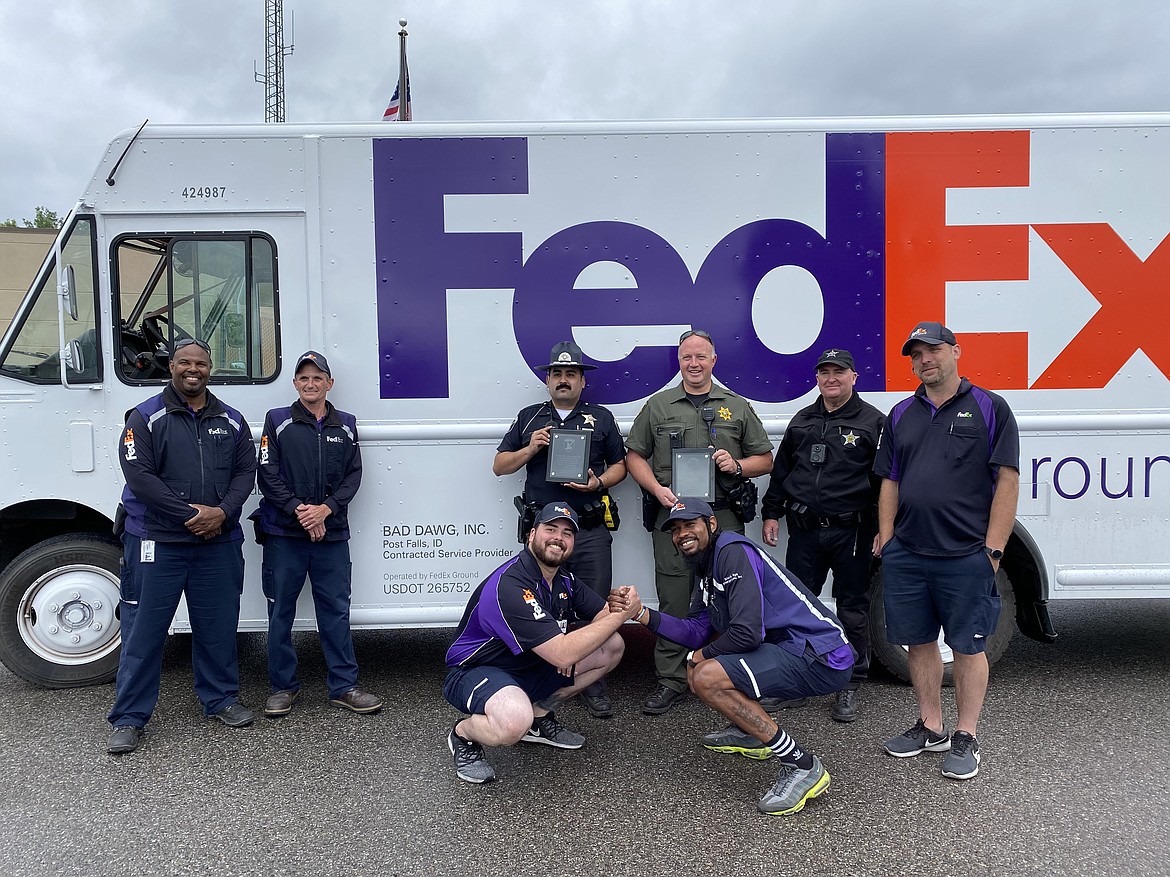 Bad Dawg Inc. FedEx workers stand with law enforcement in front of a delivery truck. From left, Roshawn Randall, Robert Palmer, ISP Trooper Enrique Llerenas, Kootenai County Sgt. Solar Larson, ISP Trooper Robert Davis, Bradley White. Front from left, Daniel Savage and Charles McCullum. (MADISON HARDY/Press)