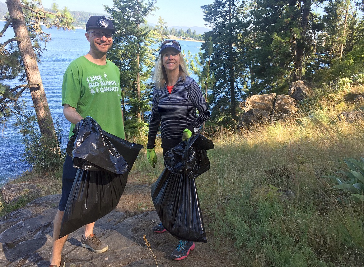 BILL BULEY/Press 
 Charles Buttermore and Pam Lohman carry bags of trash they picked up at Tubbs Hill Sunday morning during the cleanup project put on by the Tubbs Hill Foundation.