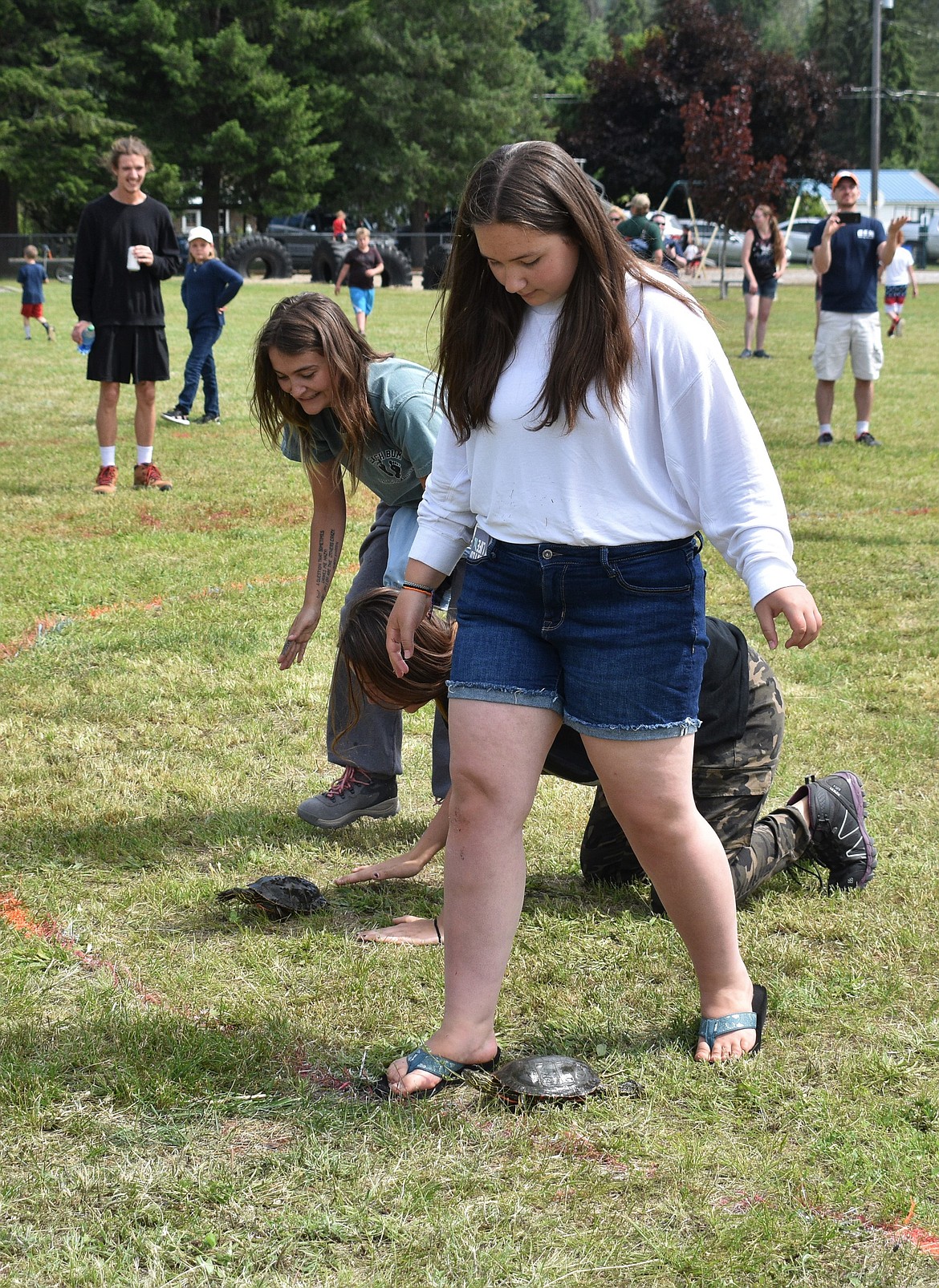 (Photo by DYLAN GREENE) 
 A teenager walks step-by-step with her turtle and guides them toward the finish.
