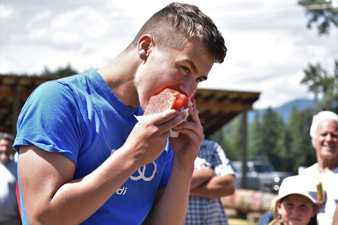 (Photo by DYLAN GREENE) 
 A teenager bites into a slice of watermelon on Saturday.