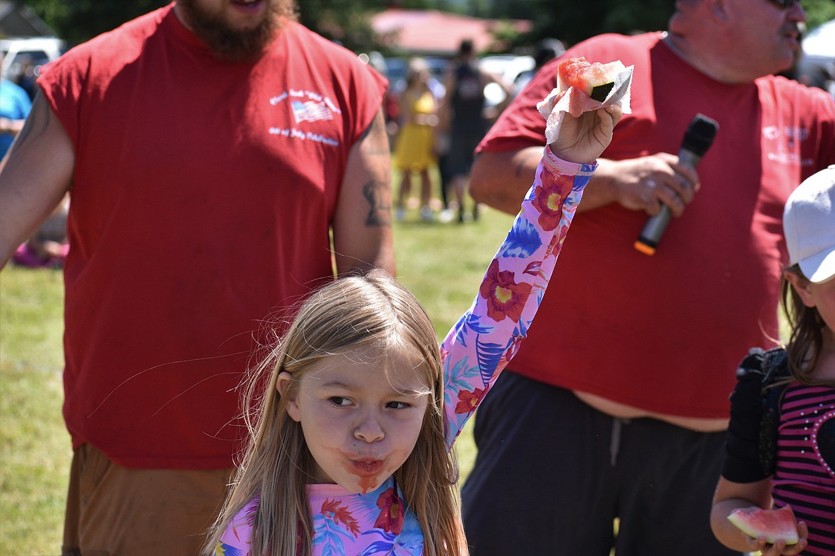 (Photo by DYLAN GREENE) 
 A young girl raises her watermelon slice in the air.