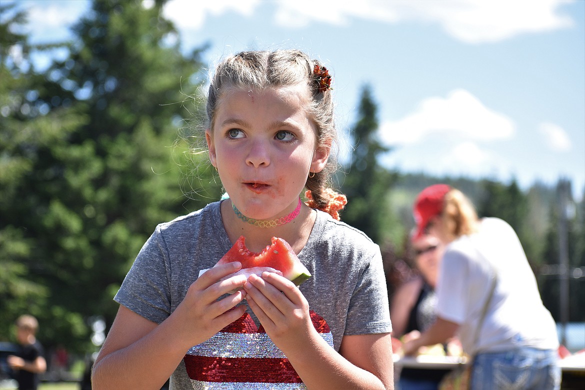 (Photo by DYLAN GREENE) 
 A young girl takes it all in while eating her watermelon.