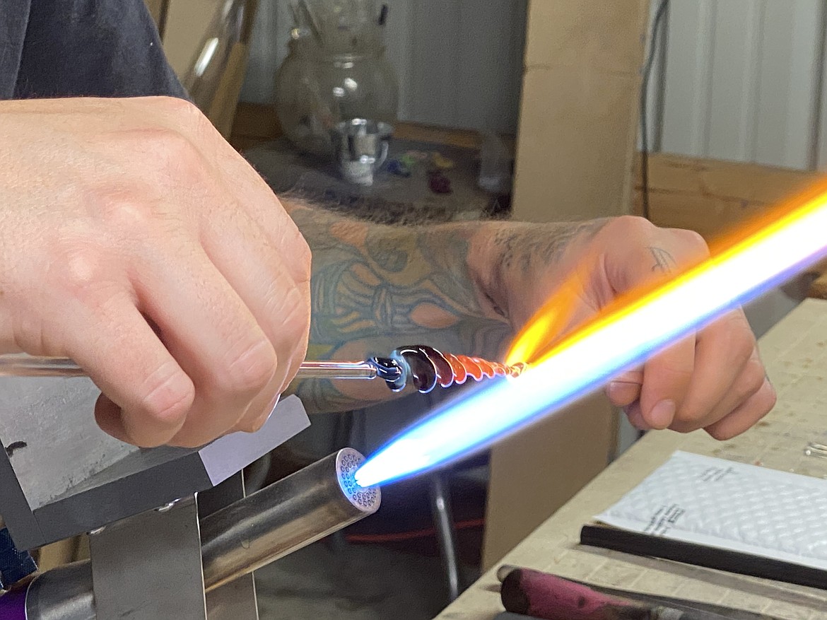 (MADISON HARDY/Press) Local glass artist Cameron Davenport, forms glas icicle over open flame.