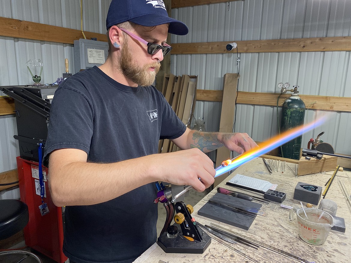 (MADISON HARDY/Press) Cameron Davenport works on custom glass memorial pieces over open flame.