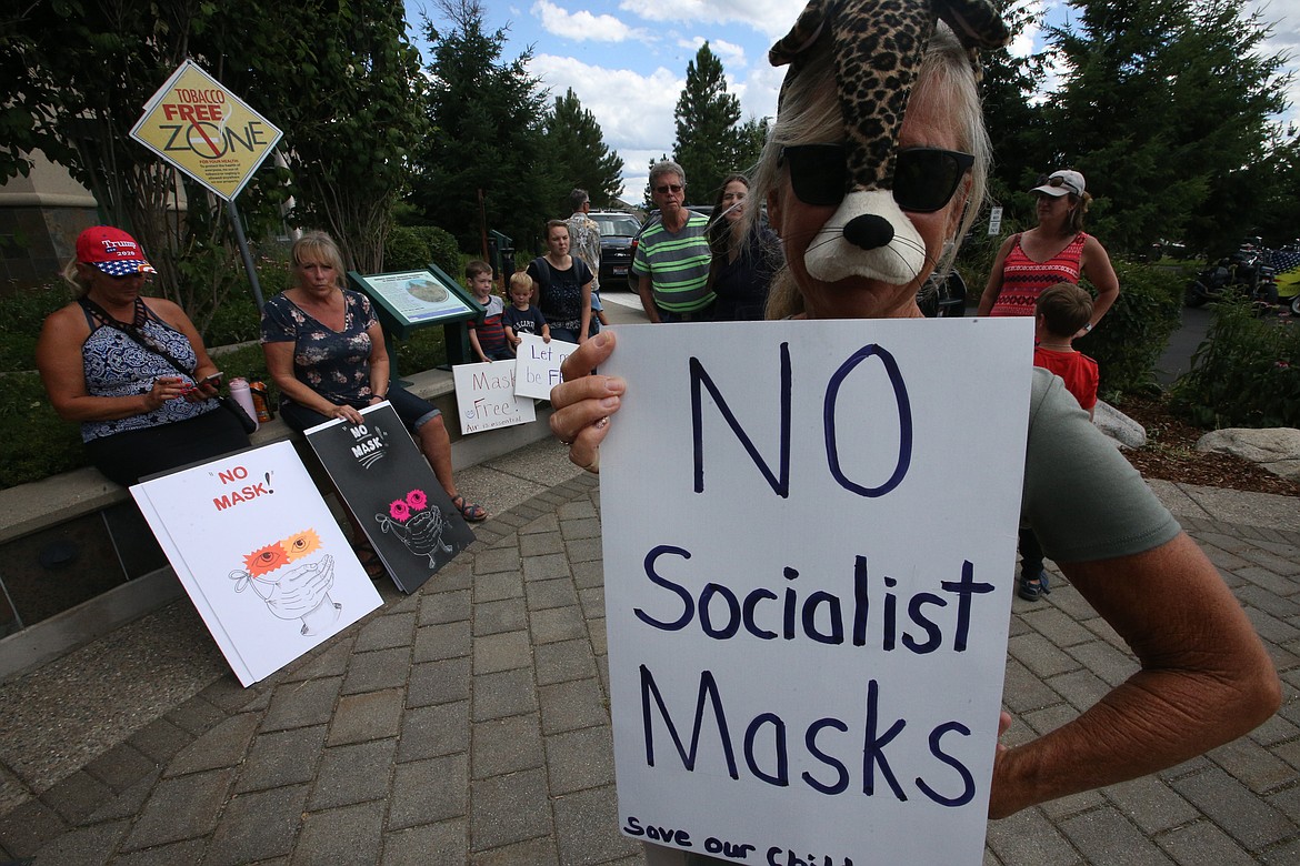 BILL BULEY/Press 
 Debbie Denney of Coeur d'Alene holds a sign and wears a mask during a rally on Friday outside the meeting of the Panhandle Health District board.