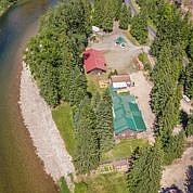 An aerial view of the St. Joe Lodge shows the historic site is situated right on the St. Joe River, cradled by evergreens.