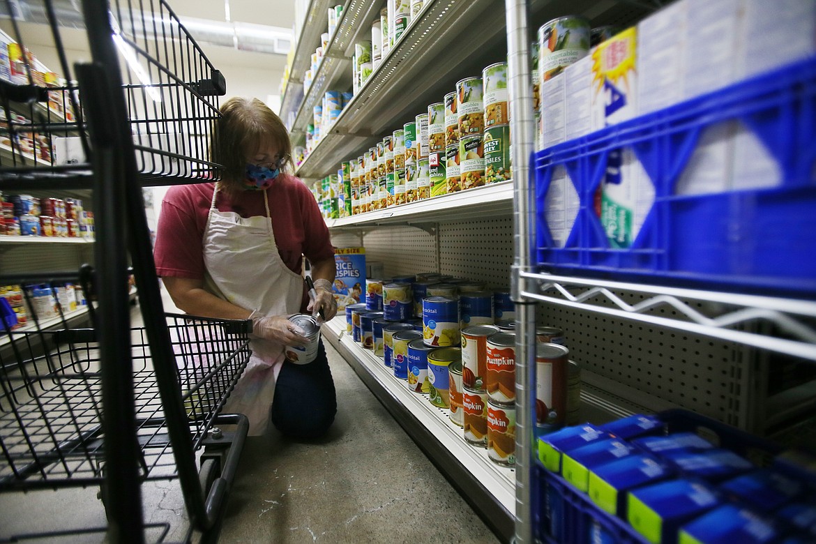 Volunteer Vi Risdon, who has been with the Post Falls Food Bank 10 years, writes points on cans in the Third Avenue Choice Market on Thursday. A larger area for the market, more parking spaces and a big commercial kitchen are on the wish list for the food bank as it looks for a new home. (DEVIN WEEKS/Press)