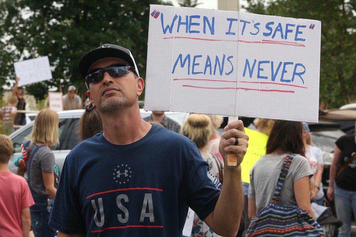 BILL BULEY/Press 
 Steve Kellerhals holds a sign outside the Panhandle Health District board meeting on Thursday.